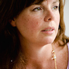 A close up of a white woman with reddish-brown hair; she is looking off to the side, away from the camera.